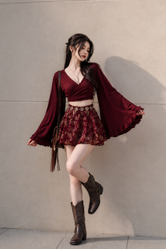 Woman in a crop top and mini skirt with cowboy boots posing outdoors