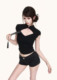 Woman in a black top and shorts holding a fan in a studio