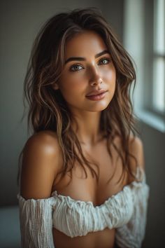 Woman with long wavy hair wearing an off-shoulder top indoors