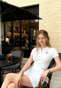 Woman with blonde hair in a white top and mini skirt at an outdoor cafe