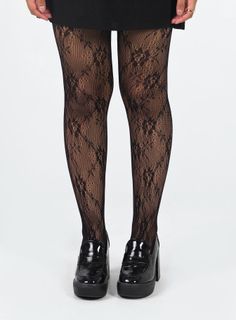 Person wearing black lace tights and platform shoes with a black skirt