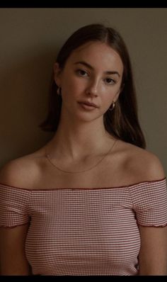 Woman with long hair wearing an off-shoulder striped top and gold jewelry