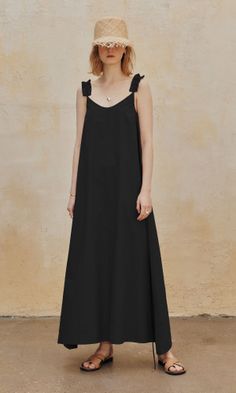 Woman in a black dress and straw hat standing outdoors