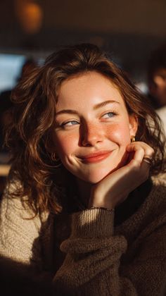 Woman with freckles and blue eyes in a sweater, illuminated by golden hour light