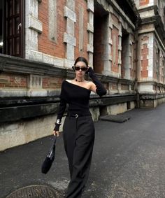 Woman in a black off-shoulder top and pants walking on a street