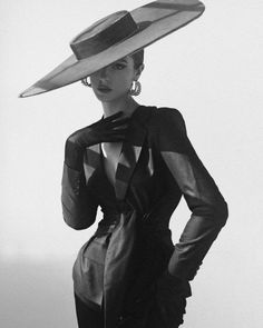Woman in a wide brim hat, suit jacket, and long gloves in black and white