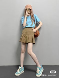 Woman in a blue t-shirt and pleated shorts posing indoors