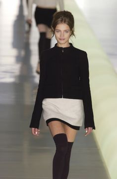 Woman in a black jacket and mini skirt with thigh-high socks on a runway