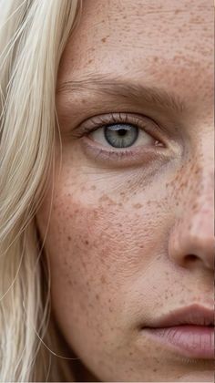 Close up of a woman's face with blonde hair, blue eyes, and freckles