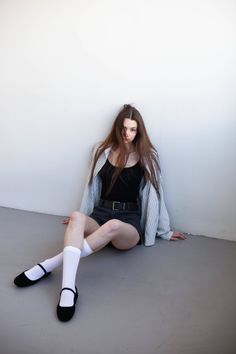 Woman with long hair sitting on the floor in a striped shirt and shorts