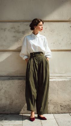 Woman in a white shirt and high-waisted olive pants standing outdoors