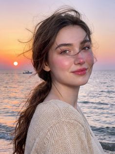 Woman with long hair on a beach at sunset, looking at the camera