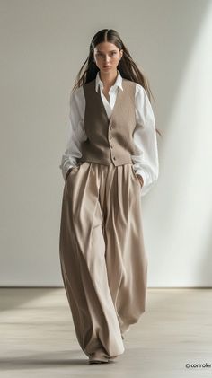 Woman in a white shirt, vest, and wide leg pants in an indoor setting