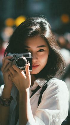 Woman with short hair holding a vintage camera outdoors