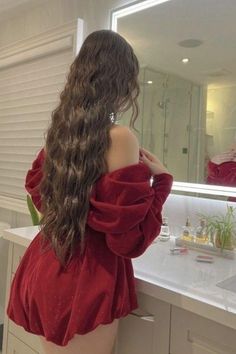 Woman with long wavy hair in a red off-shoulder dress in a bathroom