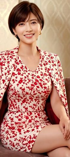Woman with short hair wearing a red floral dress and gold earrings