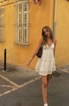 Woman in a white dress with long hair standing on a street