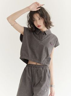 Woman in a dark grey crop top and shorts with one arm raised