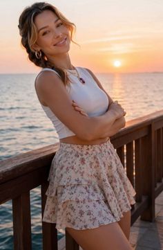 Woman in a floral skirt and crop top on a pier at sunset