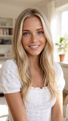 Smiling woman with blonde hair and blue eyes in a white top indoors