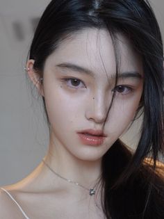 Woman with black hair and a silver necklace, hair partially covering her face