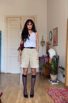 Woman in a white tank top and cargo shorts with sunglasses indoors