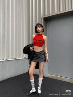 Woman in a red crop top and black mini skirt posing outdoors
