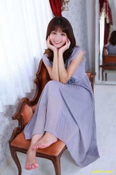 Woman in a purple dress sitting on a chair, smiling at the camera