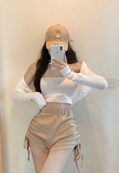 Woman in a crop top and shorts taking a mirror selfie