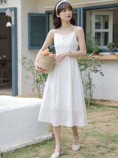 Woman in a white dress holding a basket of flowers in a garden