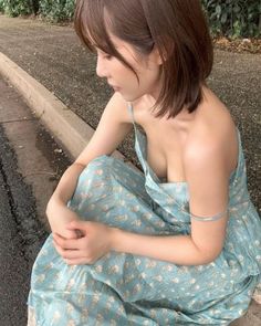 Woman in a blue floral dress sitting outdoors