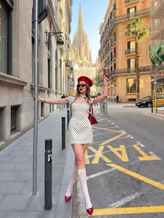 Woman in a polka dot dress and red beret posing on a city street