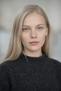 Woman with blonde hair and blue eyes wearing a dark sweater
