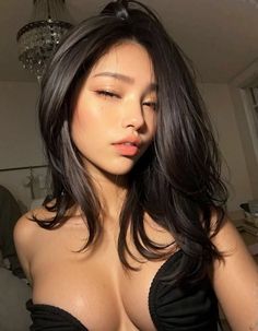 Woman with long black hair wearing a black top, showing cleavage