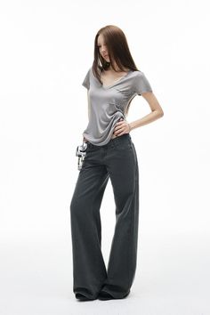 Woman with long hair in a gray t-shirt and wide leg jeans on a white background