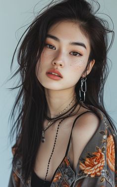 Woman with long dark hair and freckles wearing a floral jacket and jewelry