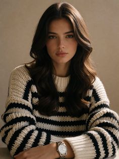 Woman with long wavy hair wearing a striped sweater and silver watch