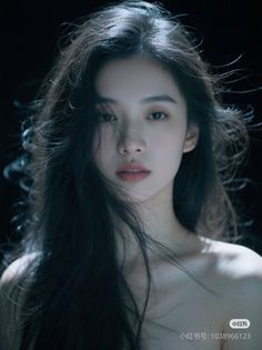 Woman with long black hair and exposed shoulders against a dark background