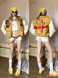 Woman in a yellow varsity jacket, white crop top, and white shorts indoors