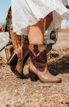 Woman in a white lace dress and cowboy boots outdoors