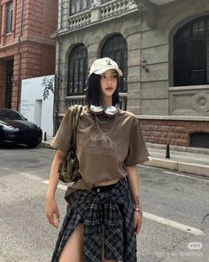Woman in a baseball cap and plaid skirt on a city street