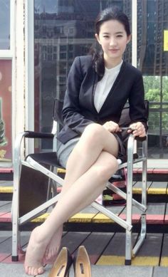 Woman in a business suit sitting outdoors with bare feet and high heels nearby