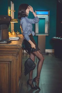 Woman in a blouse and mini skirt with black pantyhose and high heels indoors