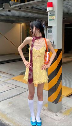 Woman in a yellow dress and red tie posing outdoors