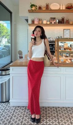 Woman in a red polka dot skirt and white top holding an ice cream cone in a cafe