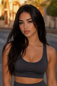 Woman with long dark hair wearing a sports bra outdoors