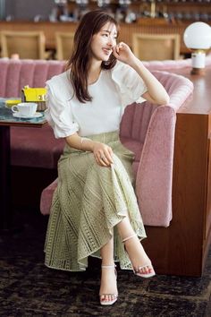Woman with long hair in a white blouse and lace skirt sitting in a cafe