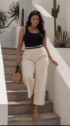 Woman in a black tank top and wide leg pants walking down outdoor stairs