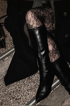 Person wearing black boots and lace stockings with a dark coat