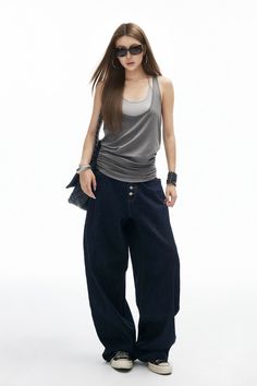 Woman with long hair wearing sunglasses, a tank top, and baggy jeans